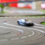 A blurry, up close view of a slot car racing along a track. The track has a groove for the car to ride on.