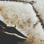 A dirty white football with visible stitches, tears, and gashes in the surface. There is also a red stain.